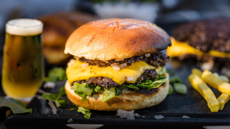 Cheeseburger with 2 smashed patties and glass of beer in background