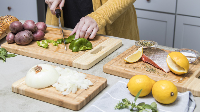 A woman cutting up and preparing food using a variety of wooden cutting boards