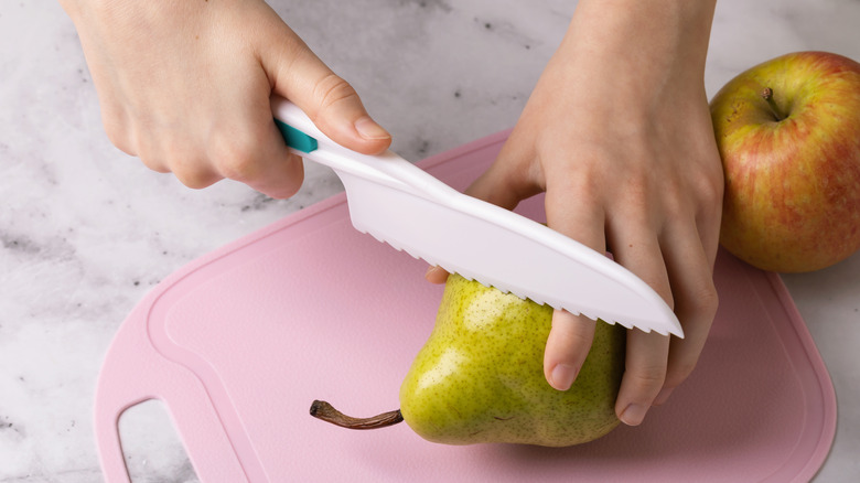 cutting a pear on plastic cutting board