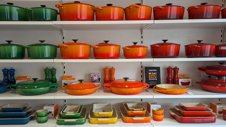 A variety of colorful Le Creuset items are on store shelves.