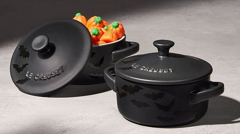 Two Bat Mini Cocottes with one filled with pumpkin candy and the lid at an angle.