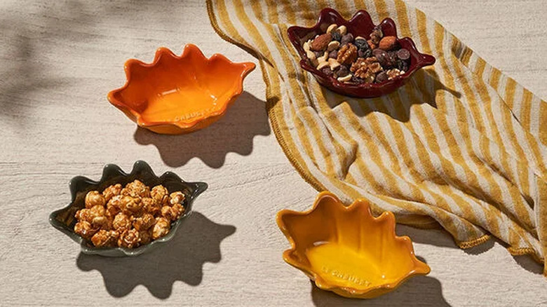 The Mini French Oak Leaf Bowls scattered around a table with a yellow stripe cloth.