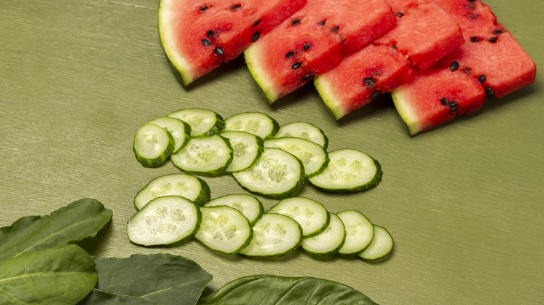 Herbs, watermelon and cucumber slices on green table