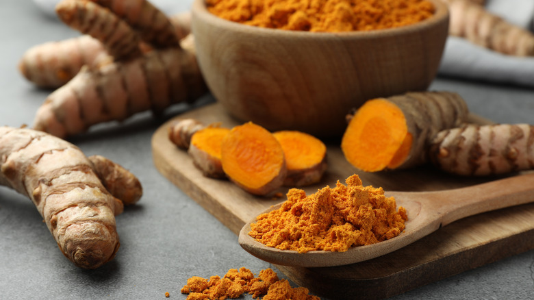 Closeup of fresh turmeric root and ground turmeric power on a table