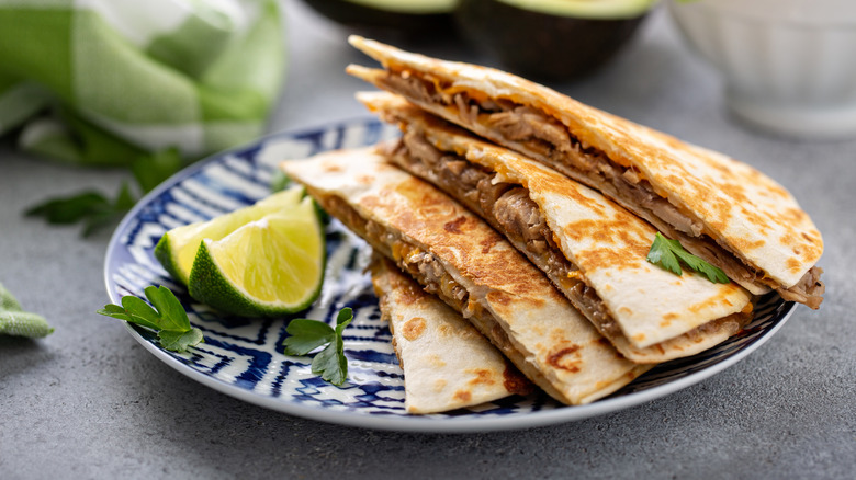 Pulled pork quesadillas on a plate with limes