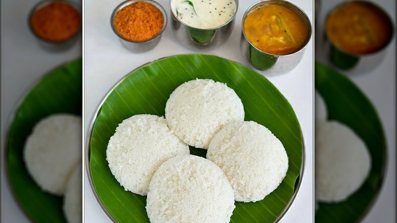 Four white cakes on a green plate with sauces