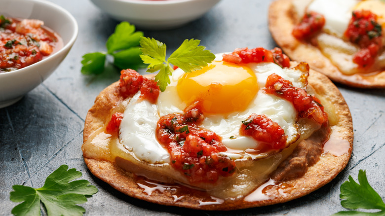 a fried egg topped with salsa over a crispy corn tortilla