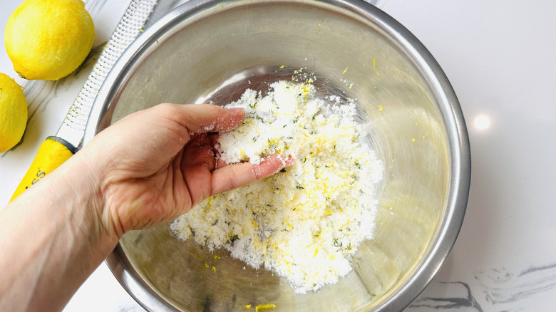 Hand grabbing lemon sugar mixture in bowl