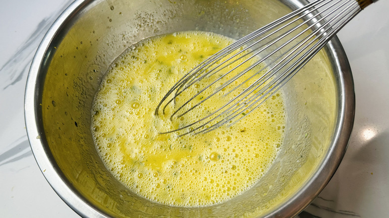 Egg mixture in bowl with whisk