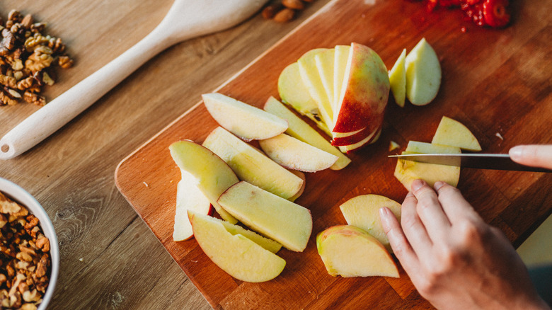 Apples being sliced on cutting board