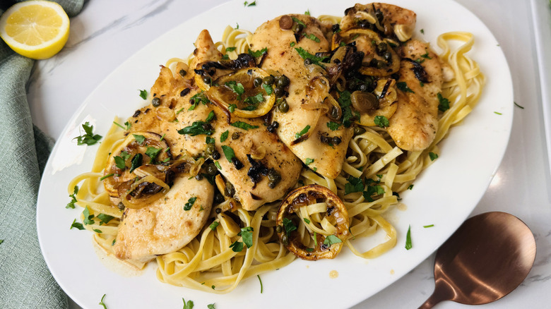 Chicken piccata with pasta on serving plate