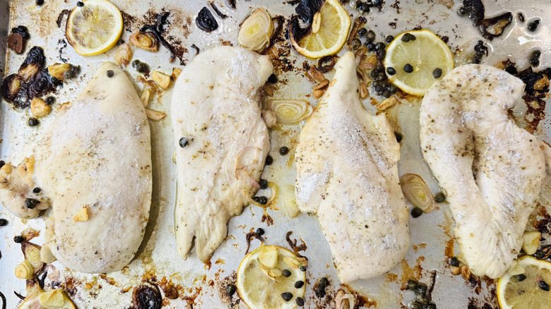 Lemony chicken piccata on baking sheet before broiling