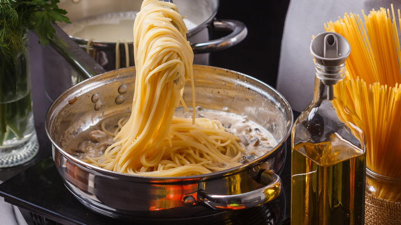 tossing pasta in sauce in skillet