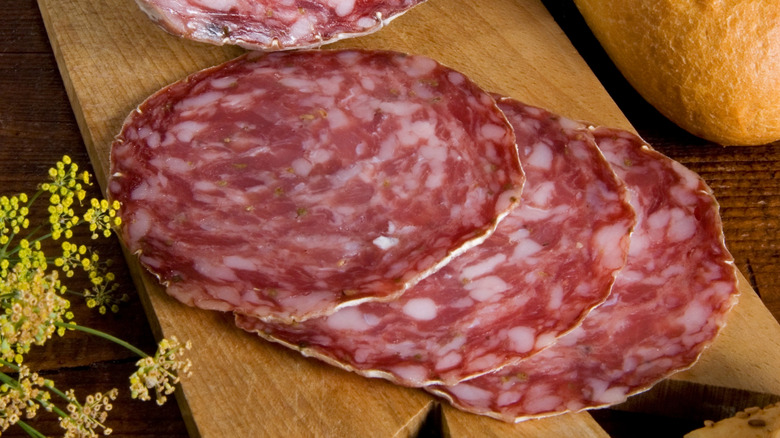 Three thin slices of finocchiona on a cutting board.