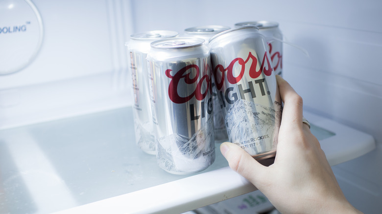 Hand grabs can of Coors Light from fridge