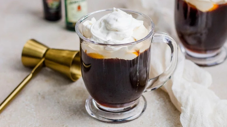 Irish coffee in a glass mug topped with shipped cream
