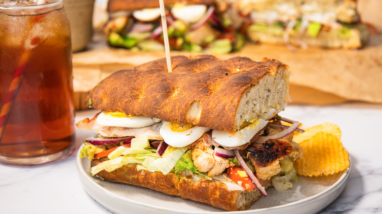 A loaded Cobb sandwich with more sandwiches in background