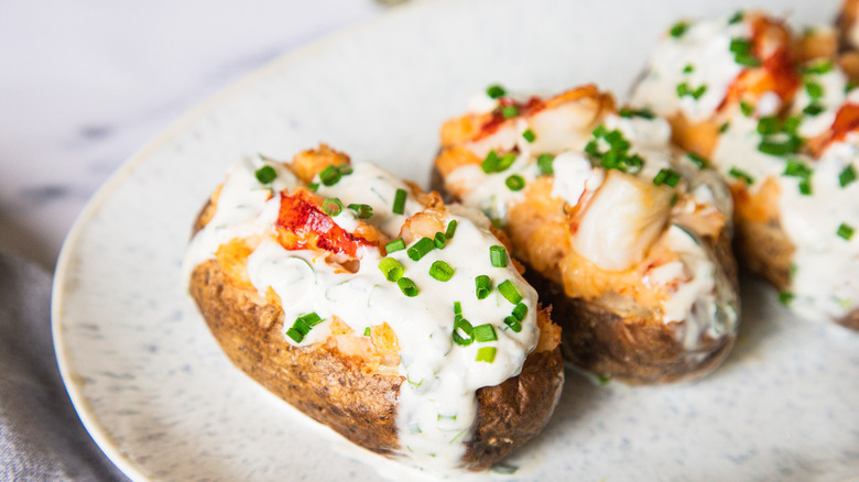 Three lobster-stuffed baked potatoes on a platter.