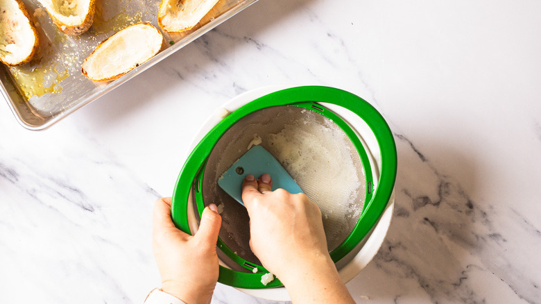 Running potato flesh through a colander.