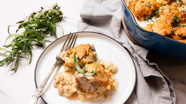 Serving of tarragon lobster pot pie on plate with skillet in background