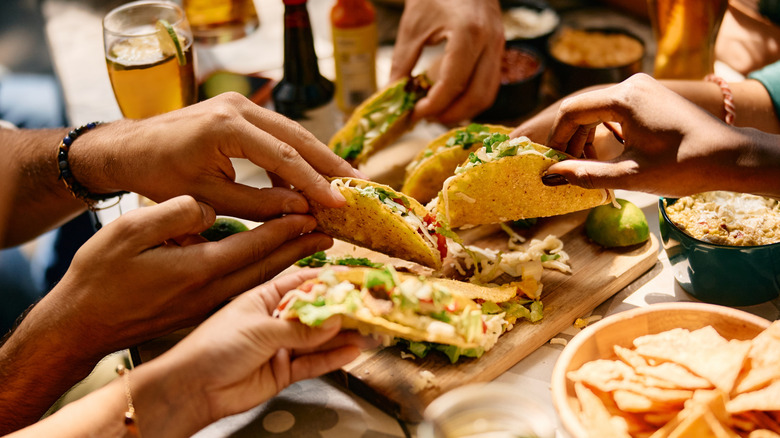 Close up of hands holding tacos at a restaurant table