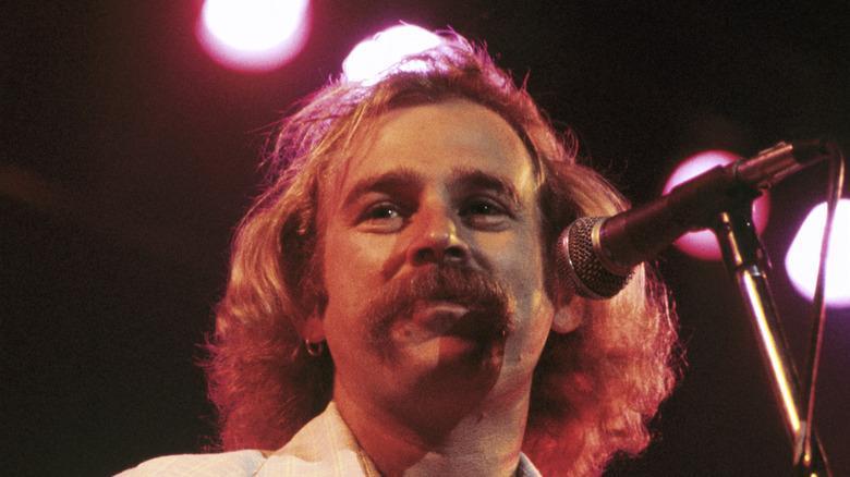 A young Jimmy Buffett sings into a microphone.