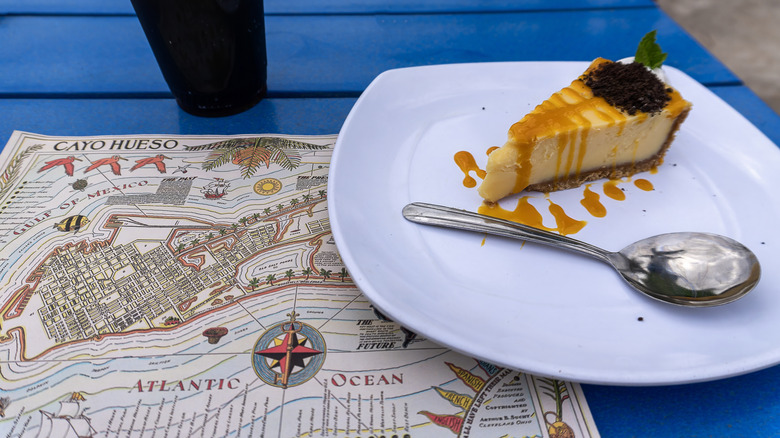 A piece of key lime pie sits on a blue table on top of a map of Key West.