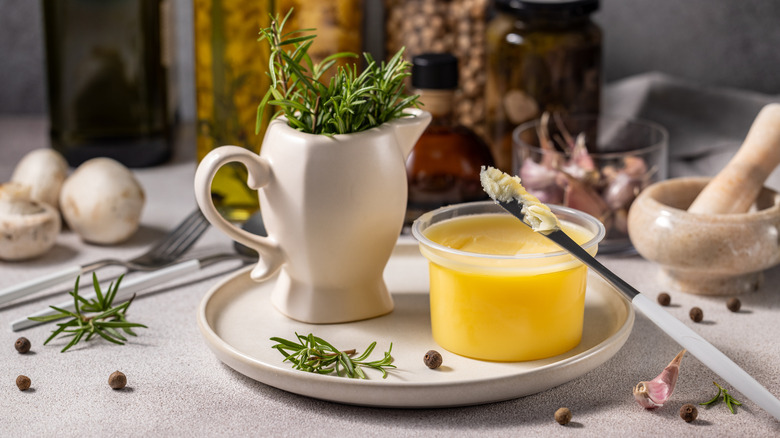 A pot of garlic butter next to a jug of rosemary