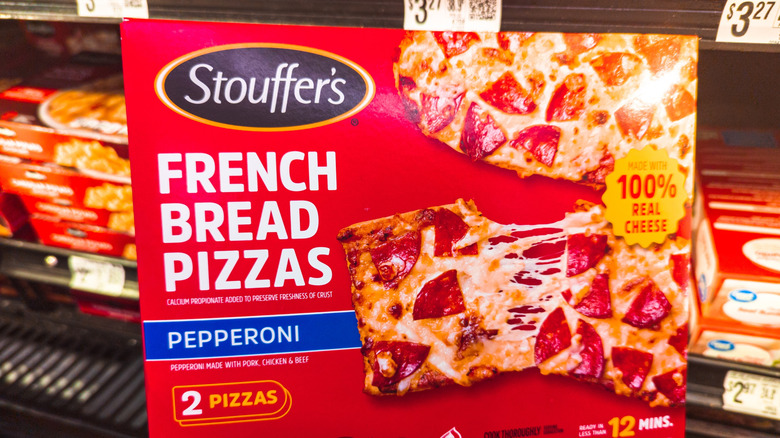 Shopper holding a box of Stouffer's French Bread Pizzas in a grocery store