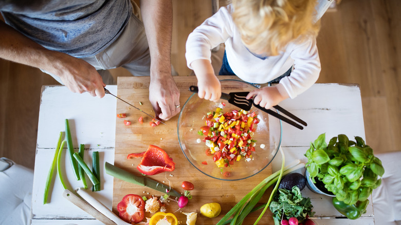 an overhead view of an adult and young child preparing a salad together