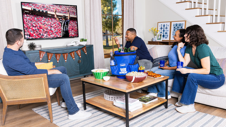 a group of friends watching football with snacks and drinks on a coffee table