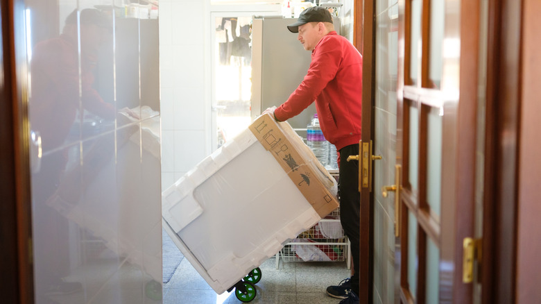Delivery person rolling a dishwasher into a kitchen