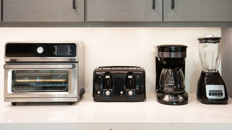 Toaster oven, toaster, coffee maker, and blender on a kitchen countertop