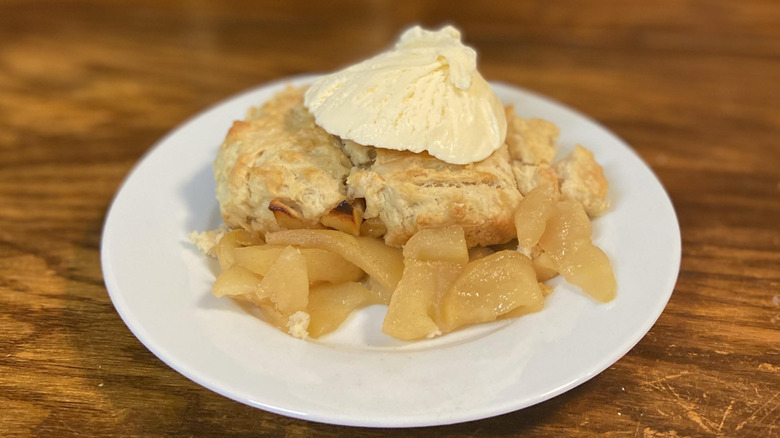 Apple John with ice cream on a white plate on a wooden table