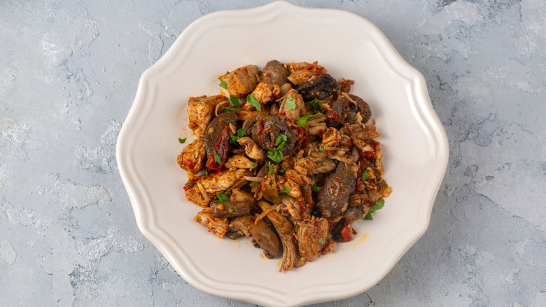 Sauteed chicken dish with mushrooms on white plate on blue patterned table