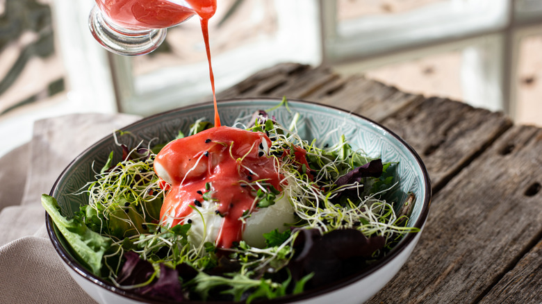 Salad bowl with red dressing on a wooden table