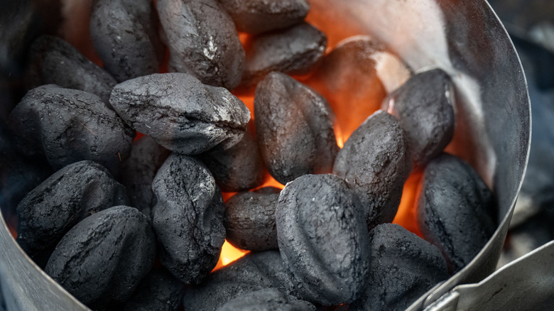 Charcoal briquettes heating up grill.