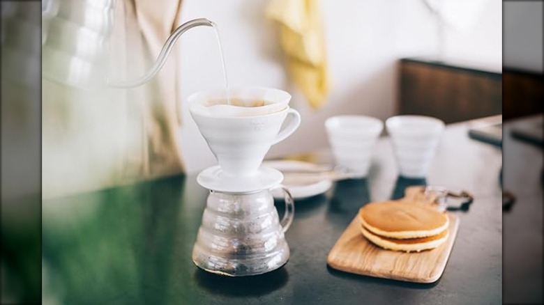 Person pouring water into a Hario coffee dripper on a kitchen counter