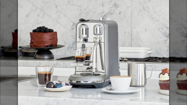 Nespresso Creatista Plus on a countertop near pods, coffee cups, and desserts
