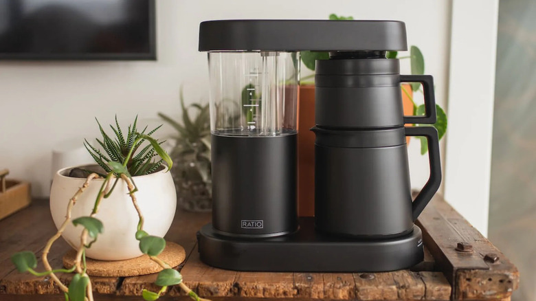 Ratio Six Coffee Maker next to potted plants on a wooden table