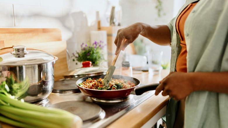 Woman stirs a skillet of food on the stove in a home kitchen