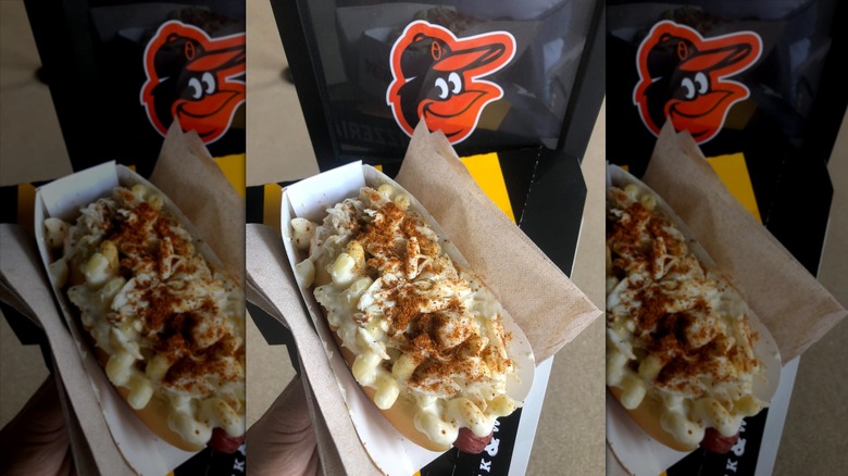 Hand holding a crab mac dog wrapped in napkins