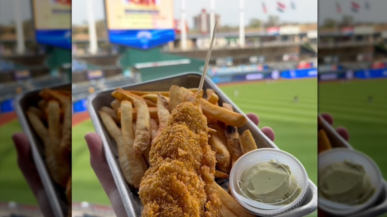 Hand holding a Sluggerrr Dog at ballpark