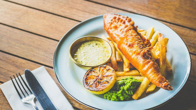 Fish and chips with grilled lemon, mushy peas, and a small bowl of tartar sauce