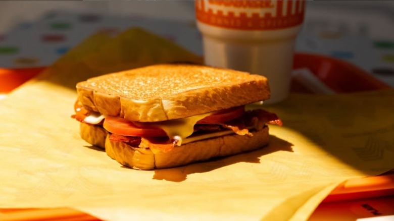 Close-up of a tray of grilled cheese from Whataburger customized with bacon, tomato, and double cheese