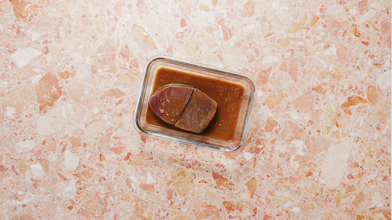Marinating tuna steaks in container