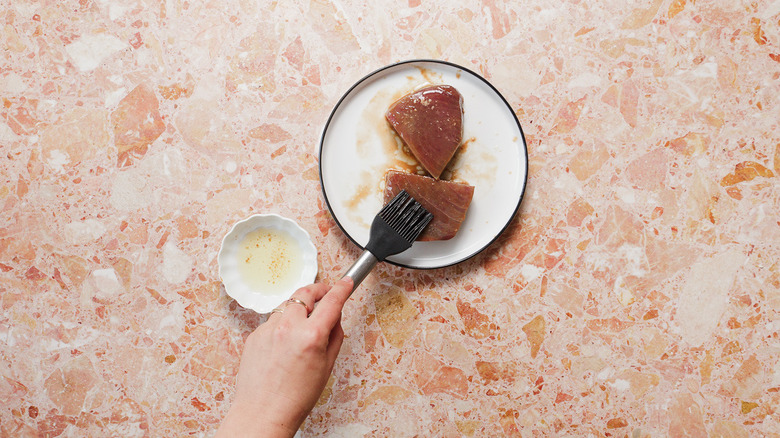 Brushing tuna steaks with oil