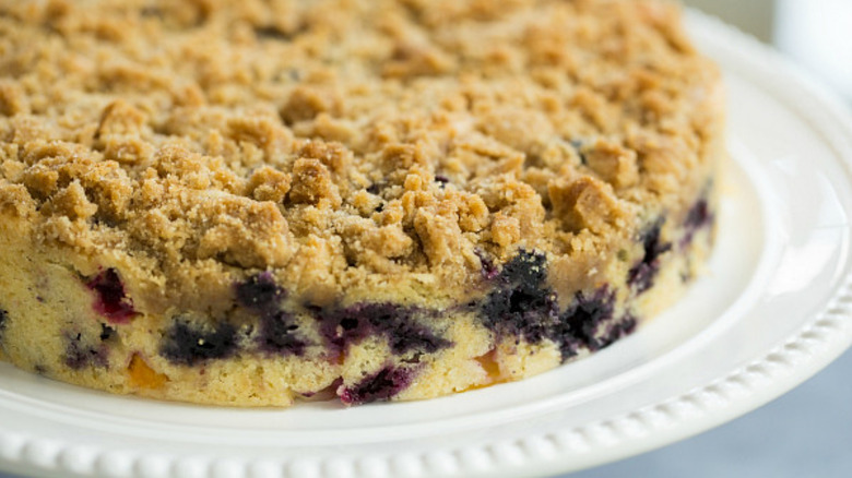 A blueberry cake on a stand with a streusel topping