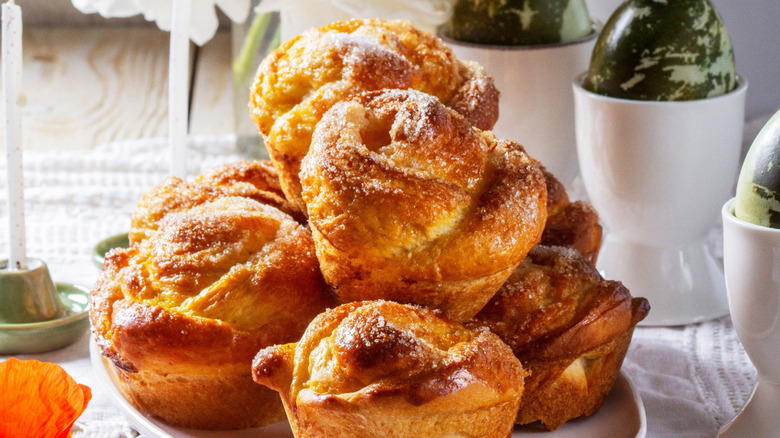 A pile of rose shaped cinnamon rolls on a plate