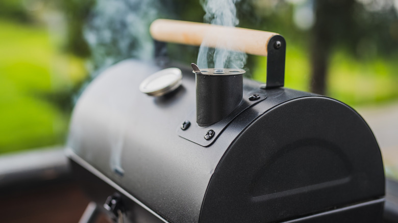 Small, closed meat smoker emanates smoke